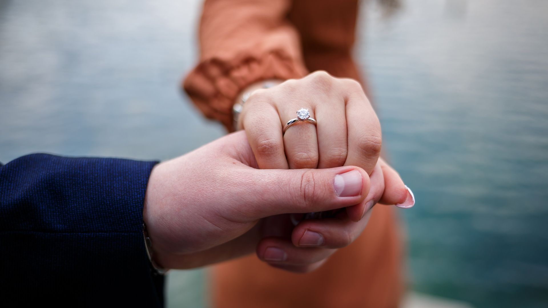 Ragazza che stringe la mano al suo fidanzato e mostra l'anello di fidanzamento